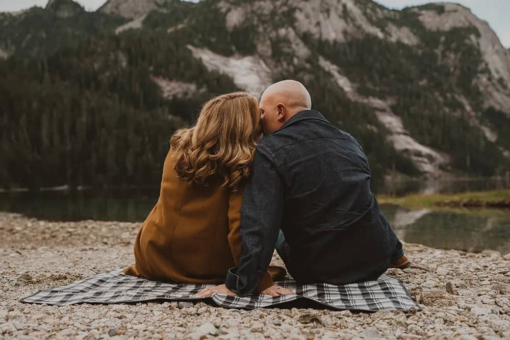 couple share a kiss in a romantic setting with a mountain backdrop