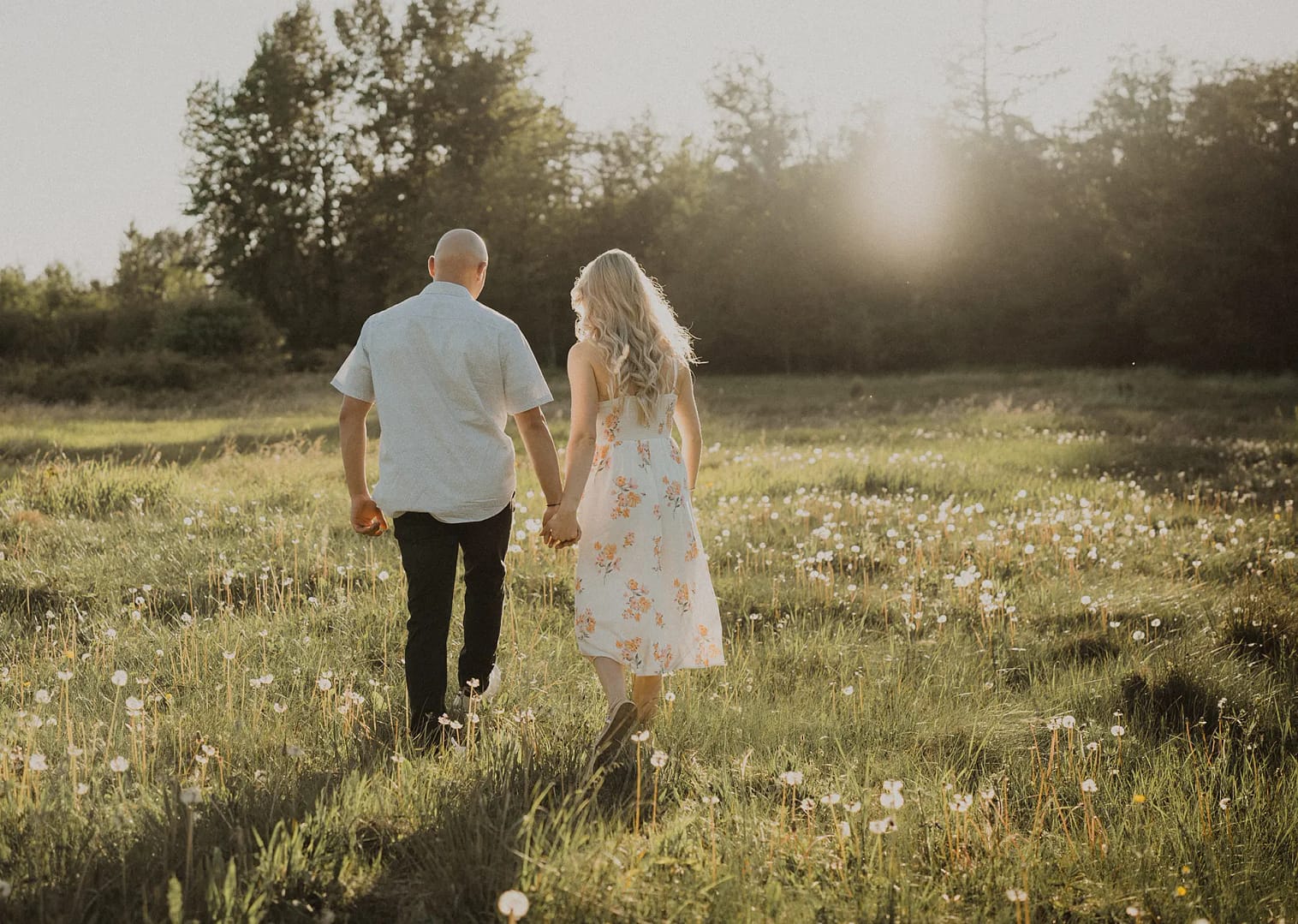 Couple holding hands walking through a field