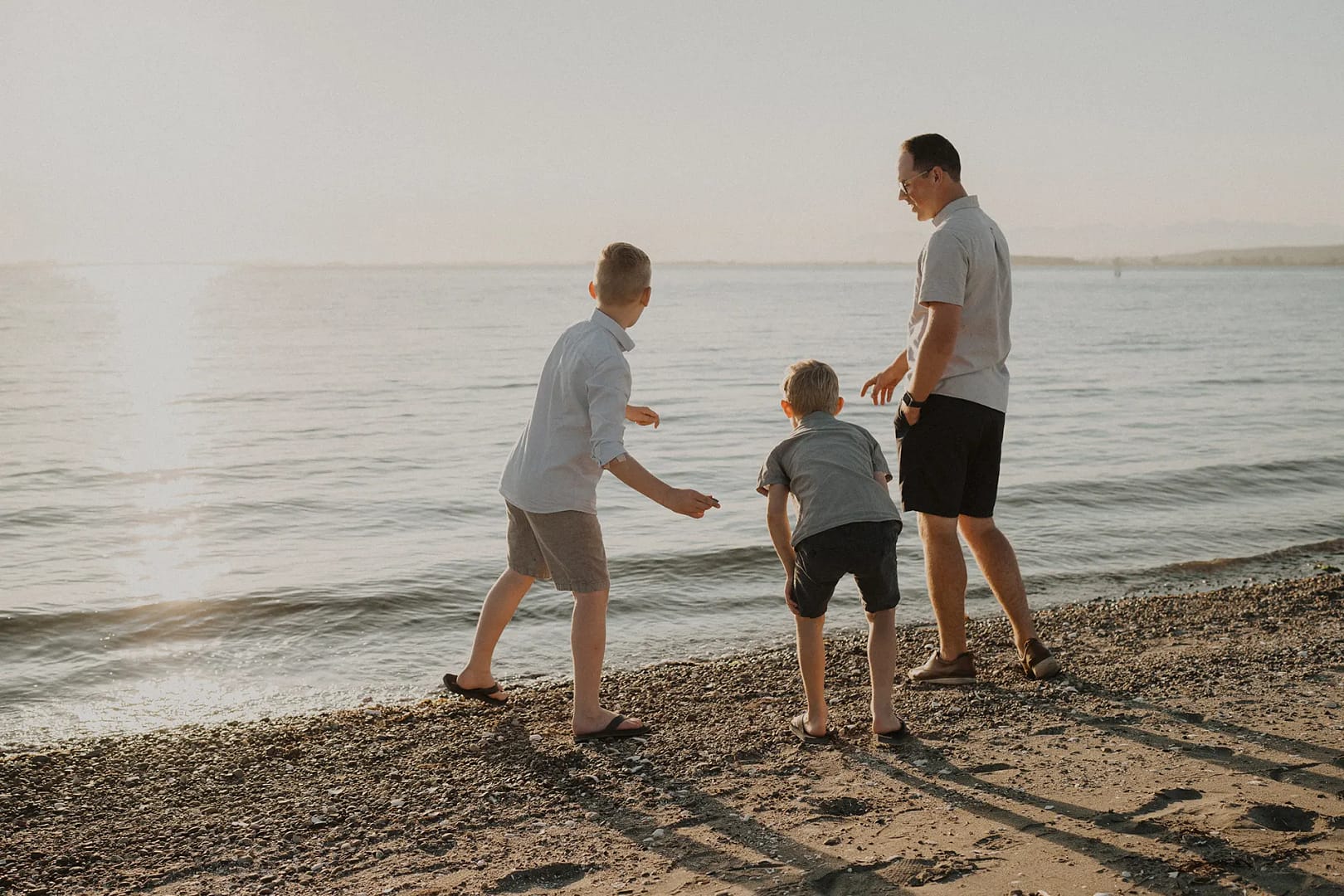 Dad and his two boys skipping rocks in the ocean