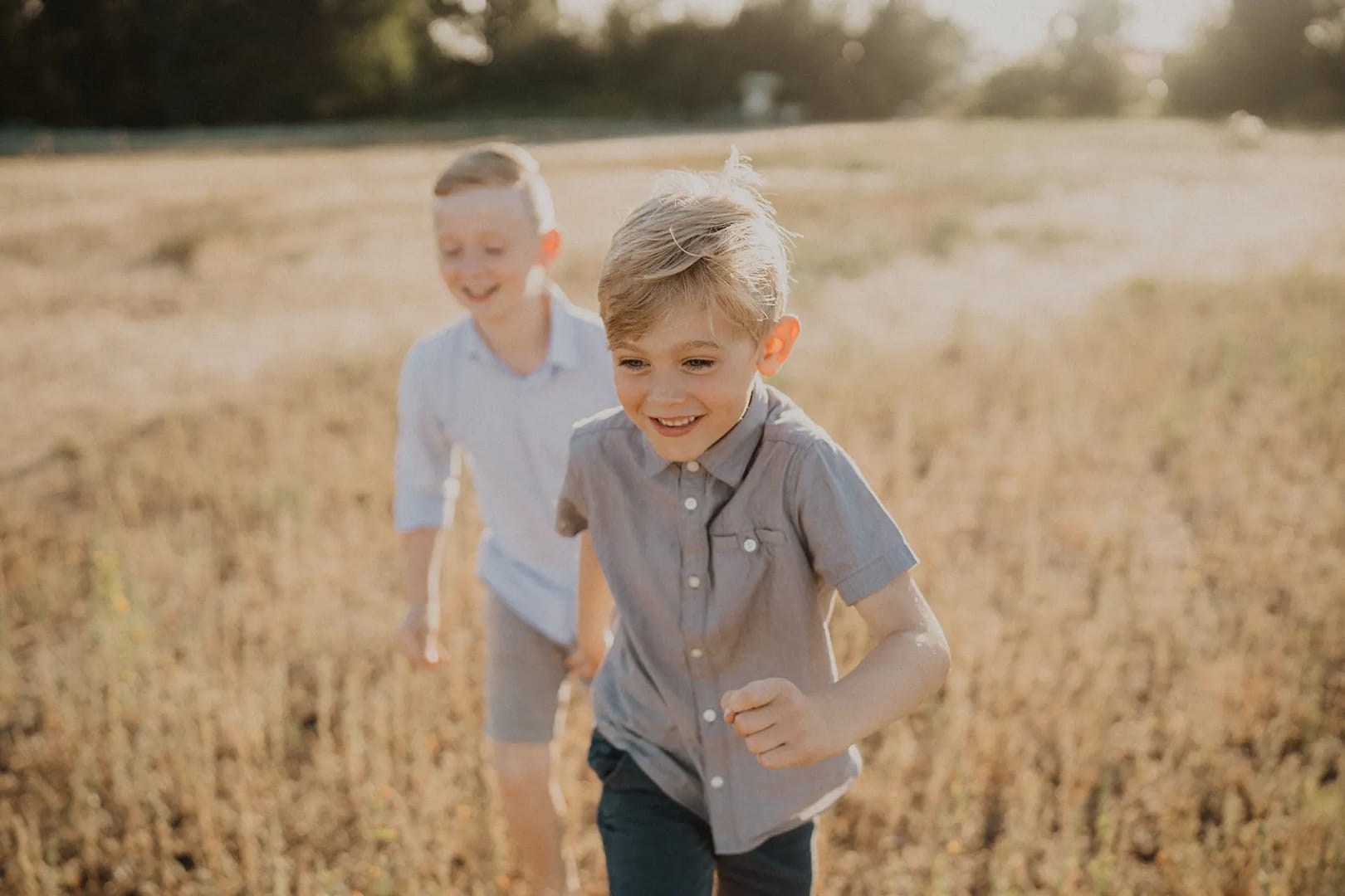 Two boys running through a sunny field