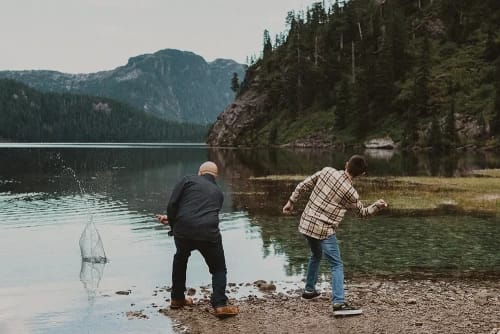 Father and son skipping rocks on a lake