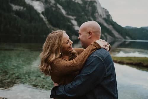 Couple laughing hugging in front of lake