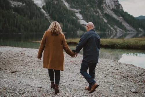 Couple holding hands walking next to a lake