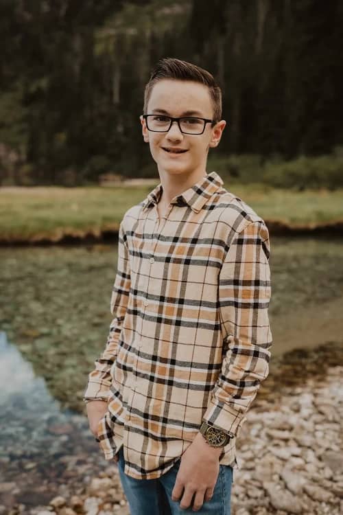 Teenage boy standing beside a lake