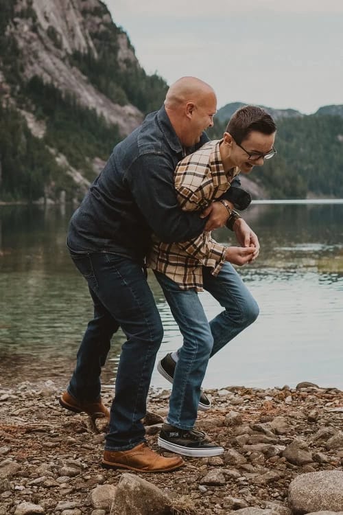 Dad laughing with son in front of a lake