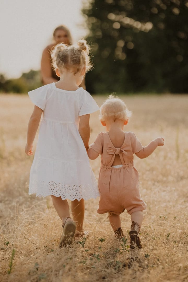 photo of two sisters holding hands in a field | Photo by Jennifer Ginn Photography