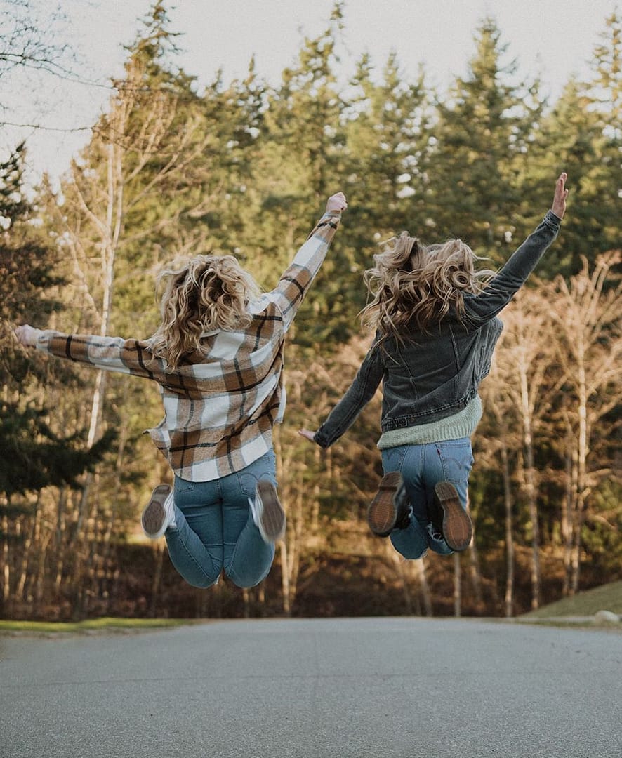 Two girls jumping in the air on a street